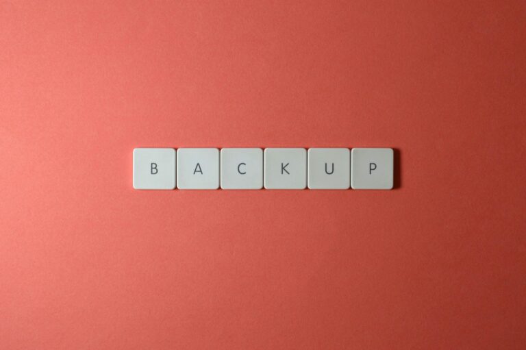 Free Close-up of keyboard keys spelling 'BACKUP' placed on a coral-colored surface. Stock Photo